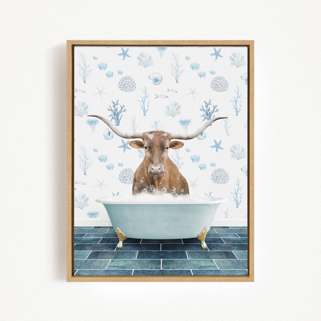 A brown cow with large horns is sitting in a white bathtub filled with bubbles, surrounded by a blue and white floral pattern on the wall behind it.