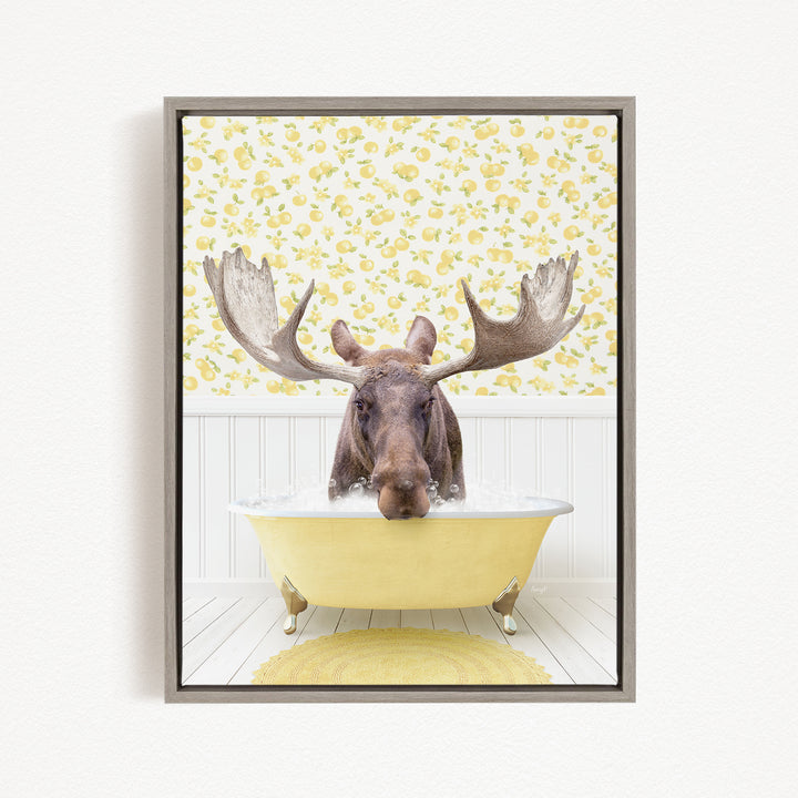 A moose with large antlers is sitting in a yellow bathtub, surrounded by a yellow and white floral pattern on the wall behind it.