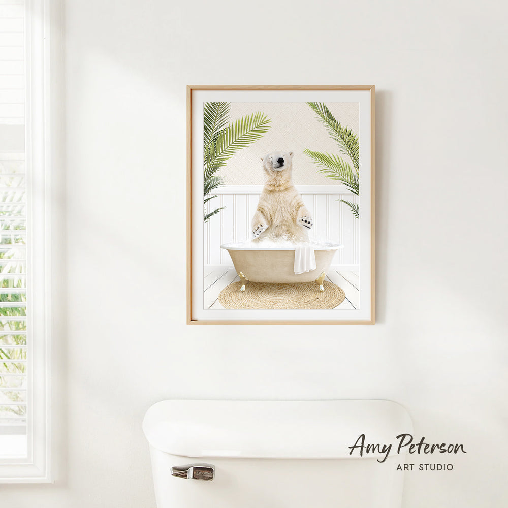 A framed image of a polar bear sitting in a bathtub, surrounded by palm leaves, is hanging on a white wall in a bathroom.