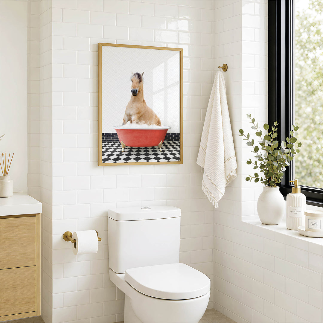 A bathroom with a white toilet, a framed picture of a dog sitting in a red bathtub, and a window with greenery outside.