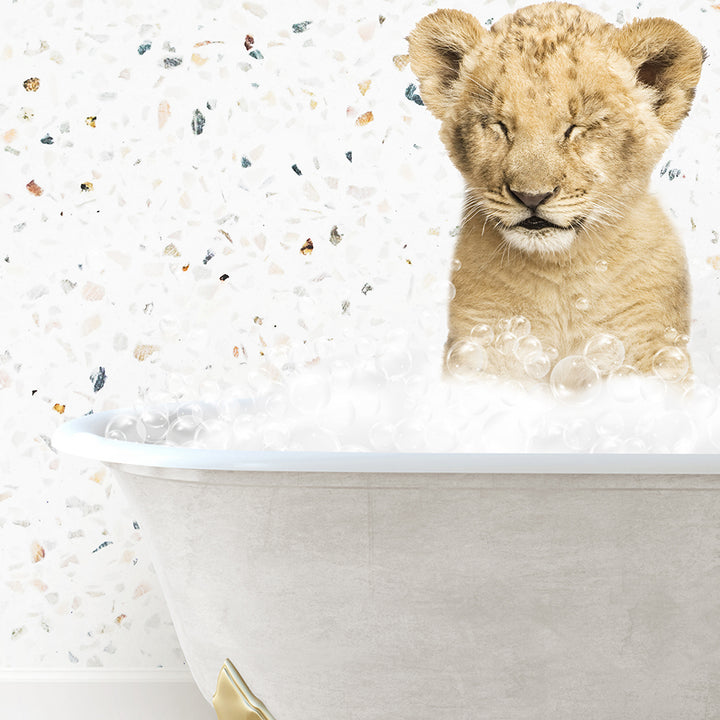 a lion cub sitting in a bathtub filled with bubbles