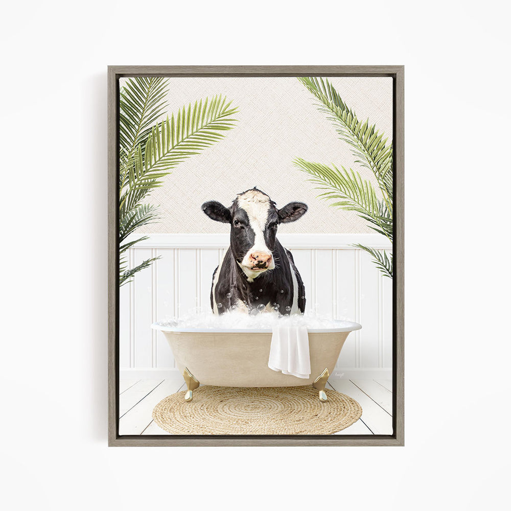 A black and white cow is sitting in a white bathtub filled with water, surrounded by green palm leaves.