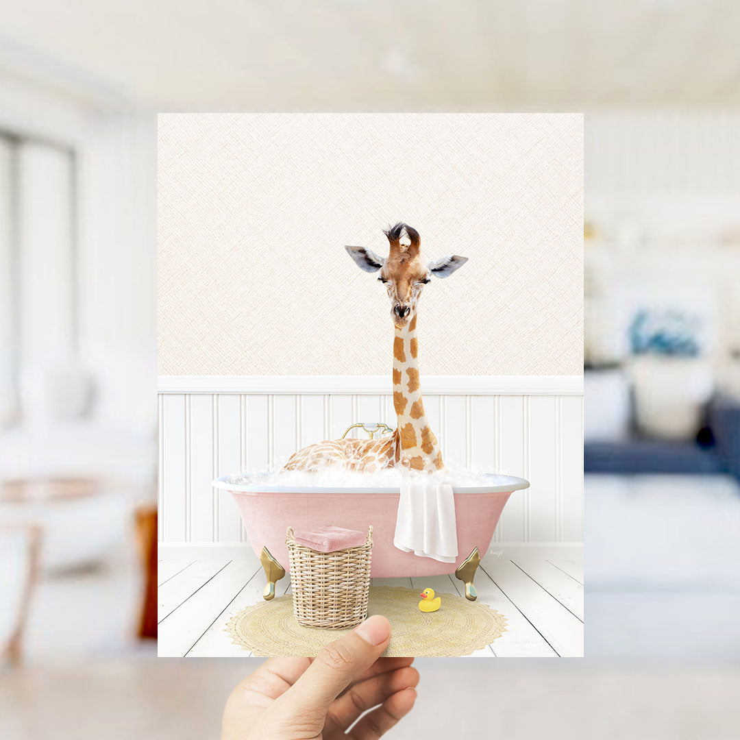 A giraffe sitting in a pink bathtub filled with bubbles, with a yellow rubber duck nearby.