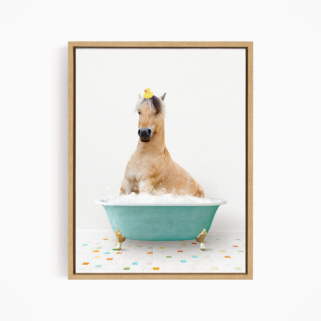 A light brown horse is sitting in a blue bathtub filled with bubbles, with a yellow rubber duck perched on its head.