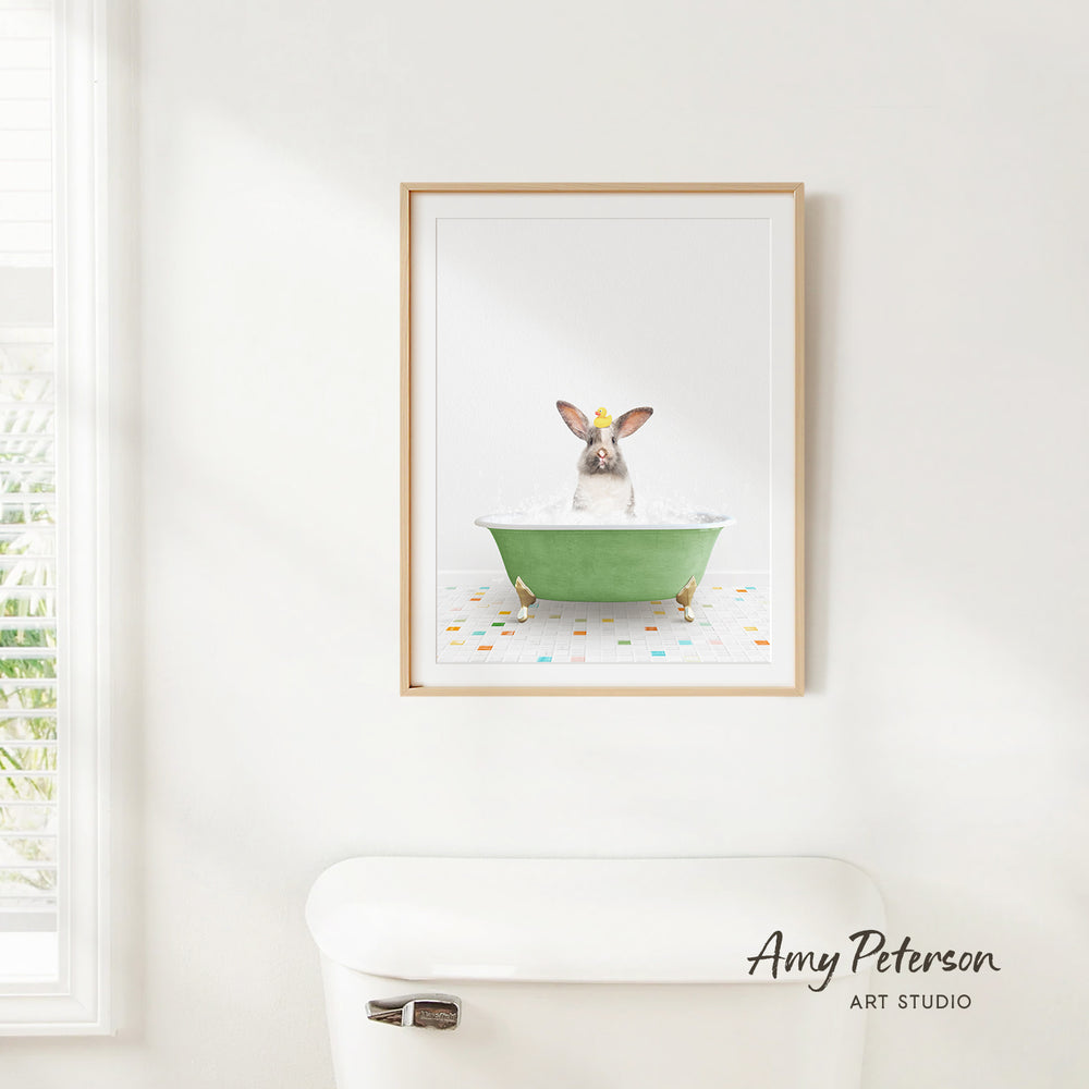 A framed image of a rabbit sitting in a green bathtub, with colorful tiles on the floor.