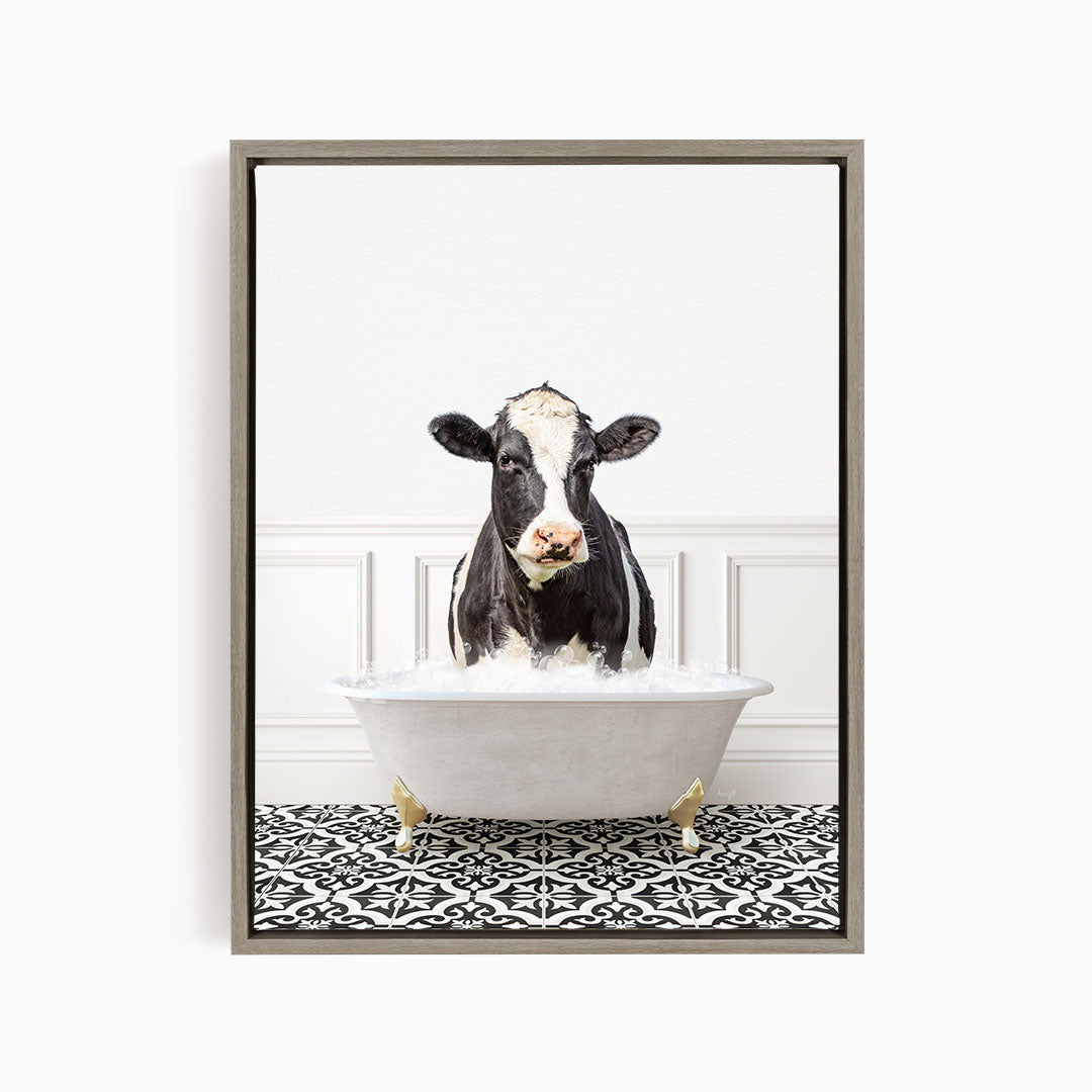 A black and white cow is sitting in a white bathtub filled with water, creating a whimsical and humorous scene.