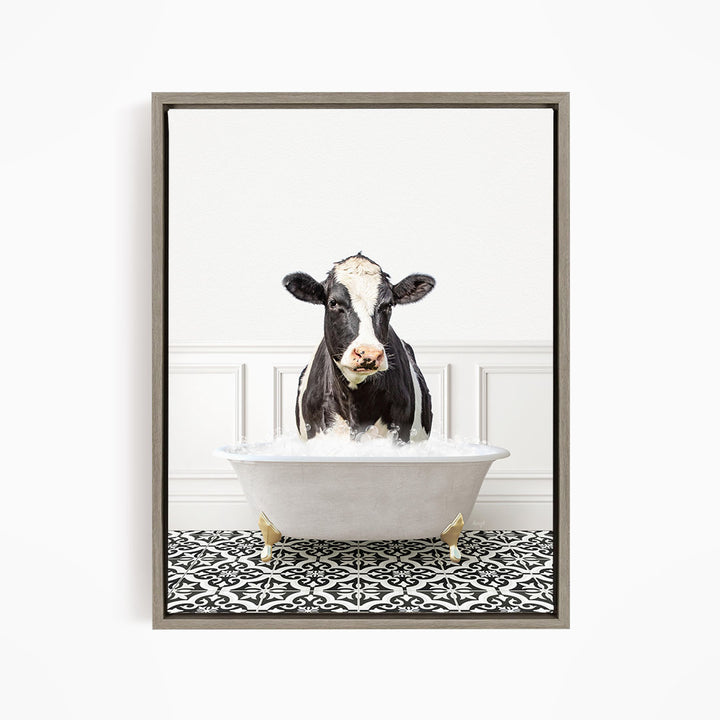 A black and white cow is sitting in a white bathtub filled with water, creating a whimsical and humorous scene.