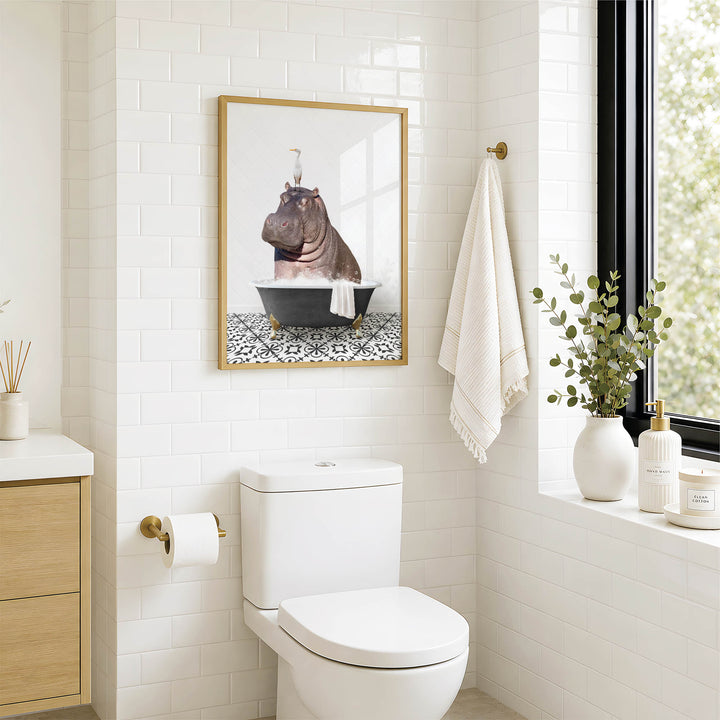 A bathroom with a white toilet, a framed picture of a hippopotamus in a bathtub, and a window with greenery on the sill.
