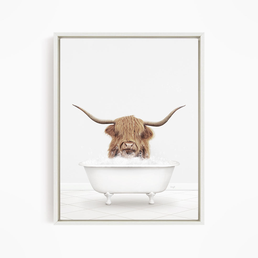 A brown cow with long horns is sitting in a white bathtub filled with water, appearing to enjoy the bath.