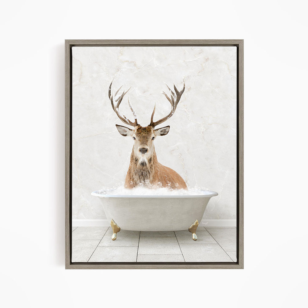 A deer with large antlers is sitting in a white bathtub, surrounded by bubbles, against a white marble wall.