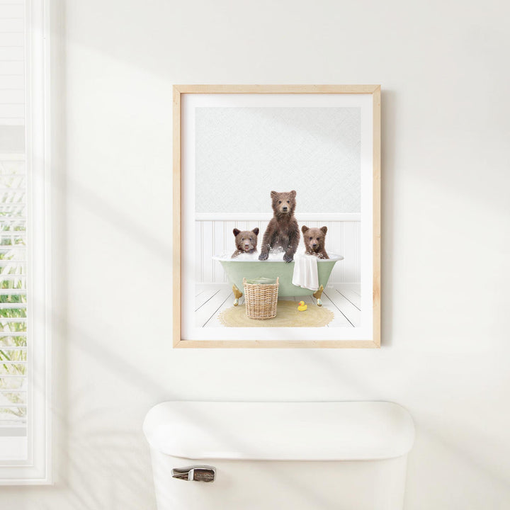 A framed image of three bears sitting in a bathtub, with one bear sitting on the edge of the tub and the other two bears sitting inside the tub.