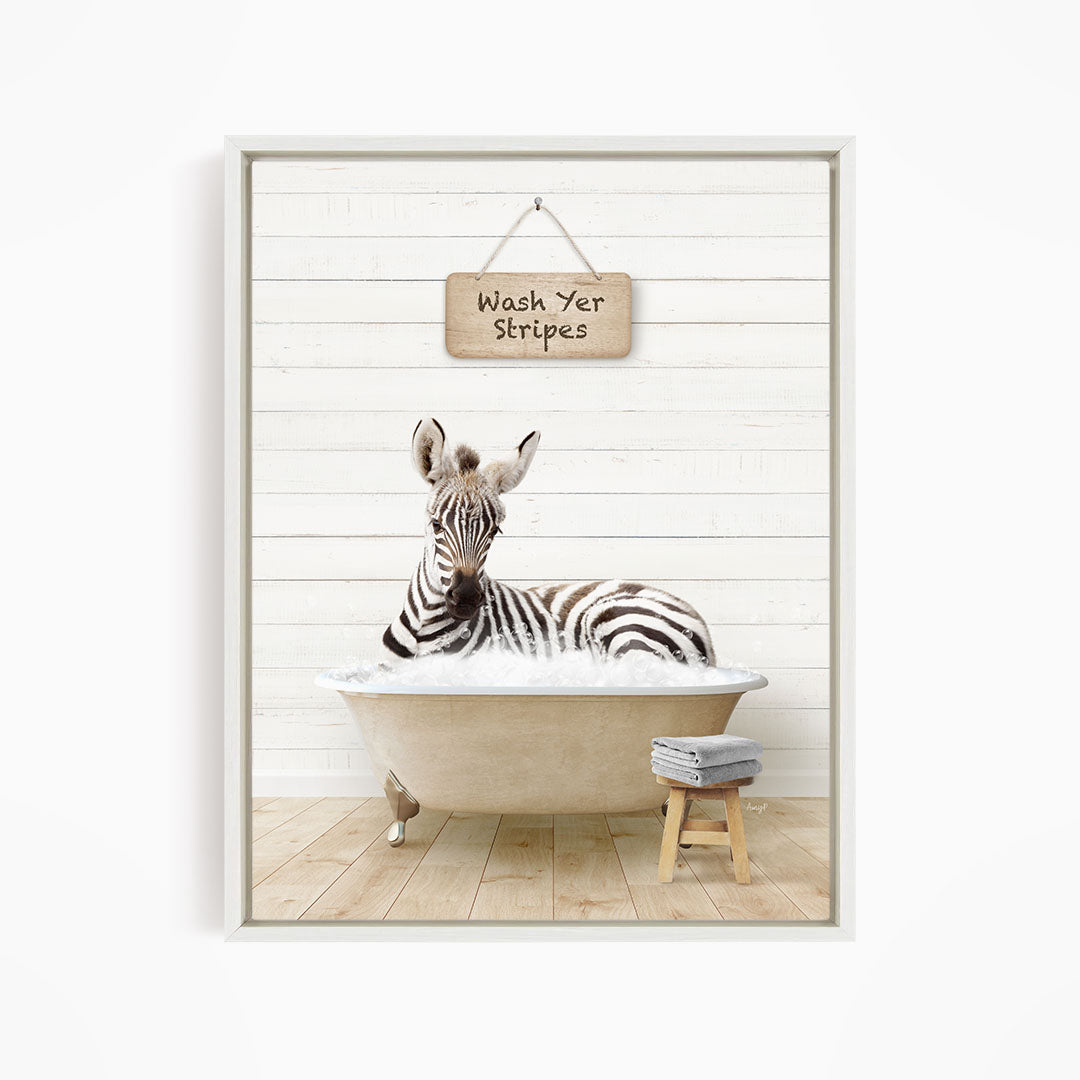 A zebra is sitting in a bathtub, with a sign above it that says "Wash Yer Stripes".