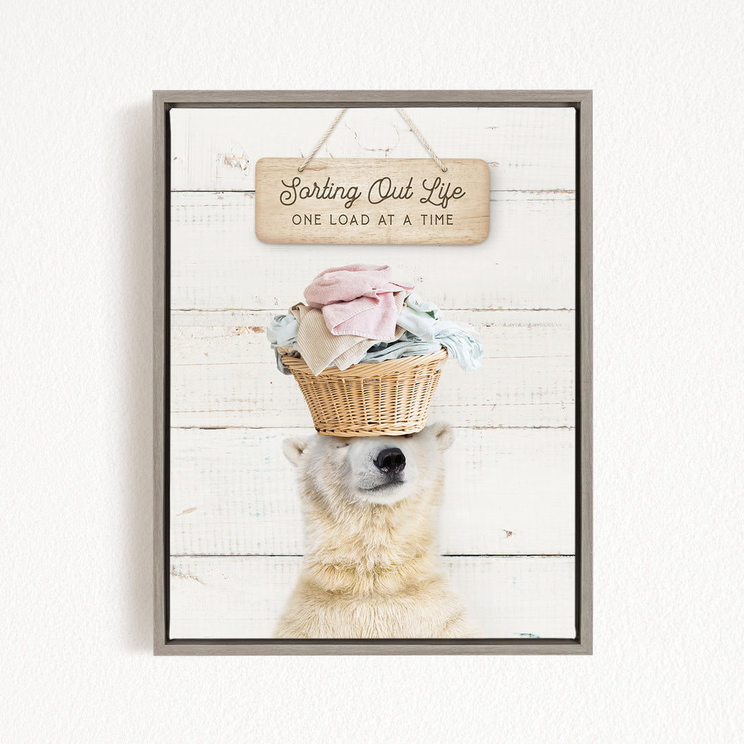 A polar bear balancing a basket of laundry on its head, with a sign above that reads "Sorting Out Life One Load at a Time".
