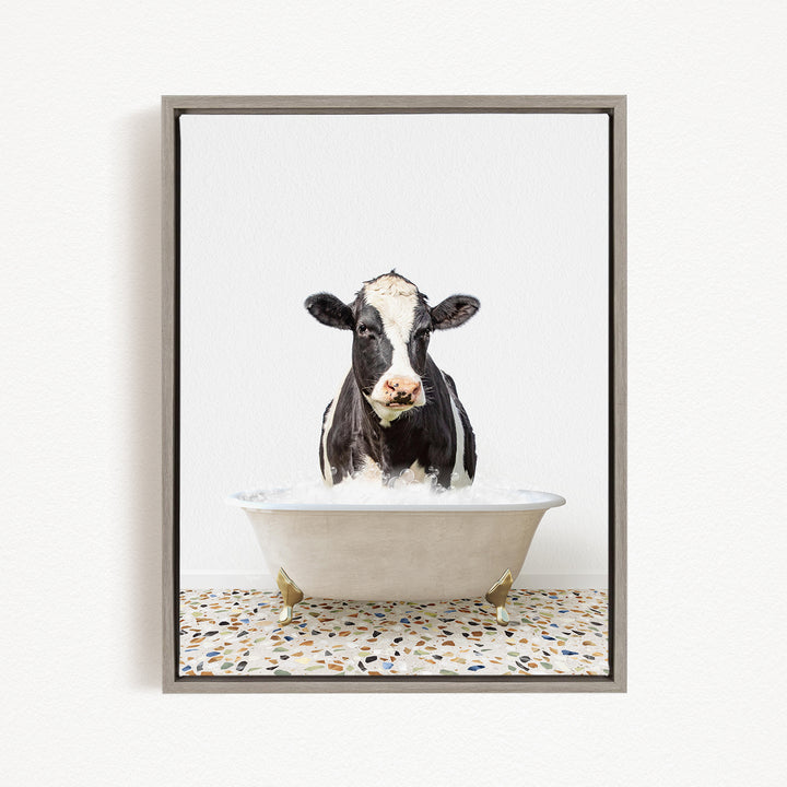 A black and white cow is standing in a white bathtub filled with water, creating a whimsical and humorous scene.