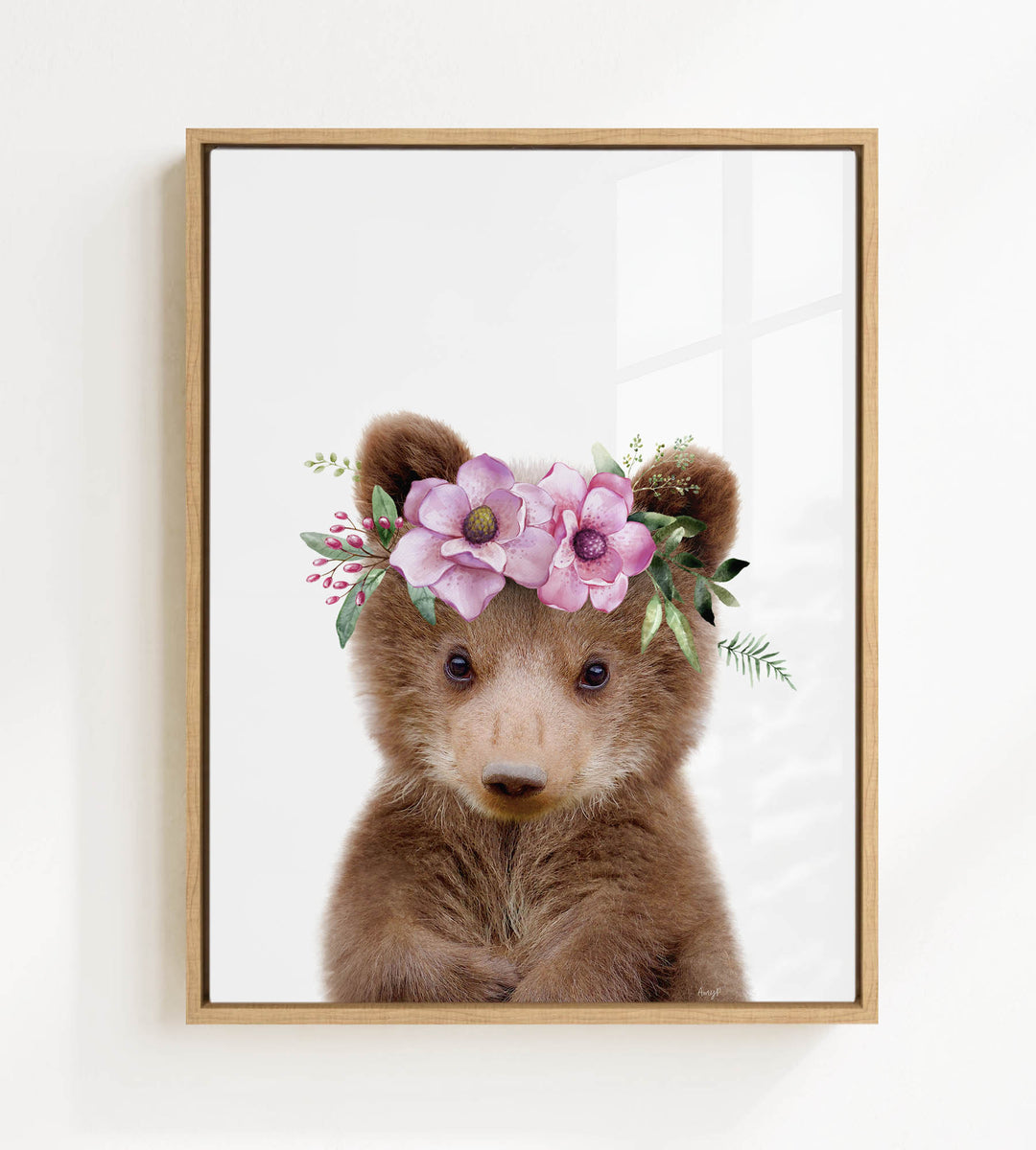 A cute brown bear wearing a floral crown of pink flowers and greenery.