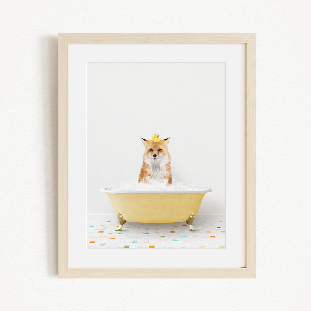 A fox is sitting in a yellow bathtub filled with bubbles, with a rubber duck perched on its head.