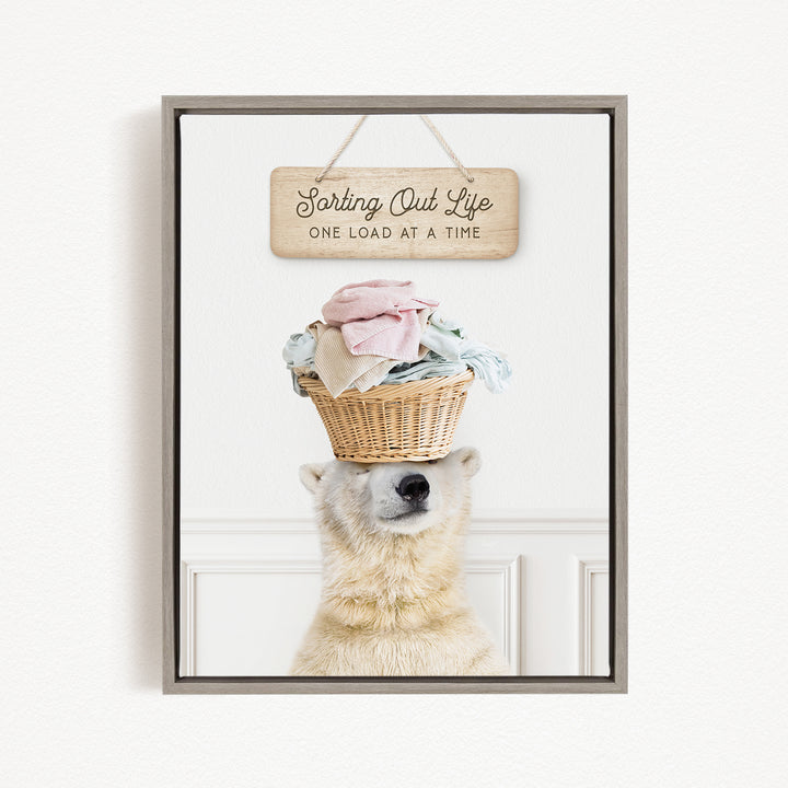 A polar bear balancing a basket of laundry on its head, with a sign above that says "Sorting Out Life One Load at a Time".