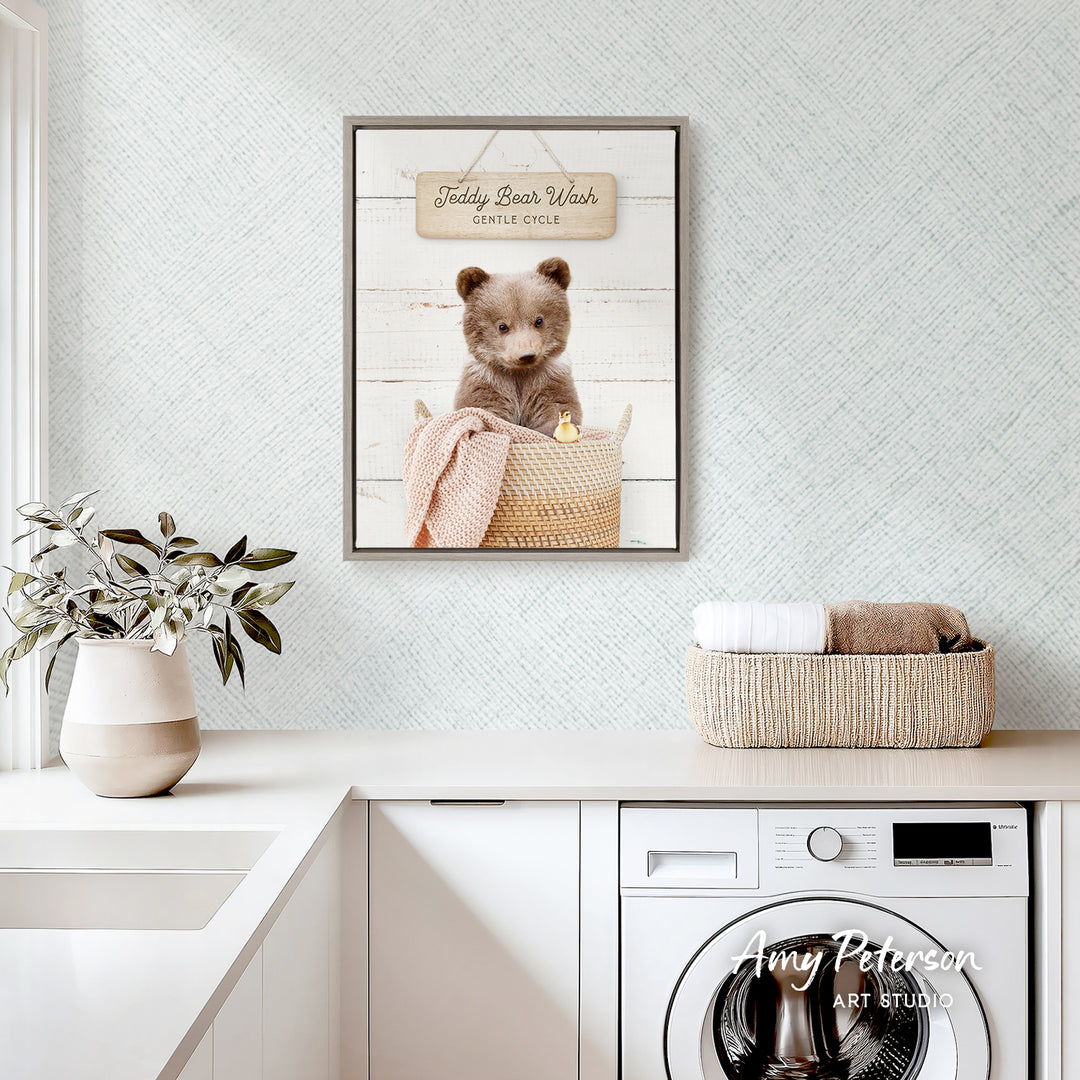 a framed picture of a teddy bear sitting in a basket, placed on a white countertop in a kitchen setting.