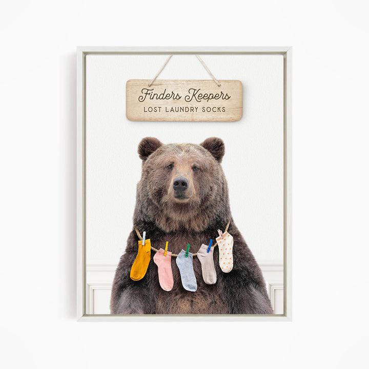 A wooden sign with the text "Finders Keepers" hangs above a bear wearing a pile of colorful socks.