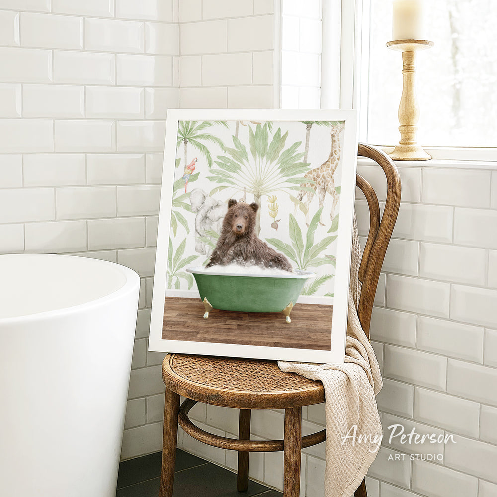 A framed image of a bear sitting in a green bathtub, surrounded by tropical foliage, is displayed on a wooden chair in a bathroom setting.