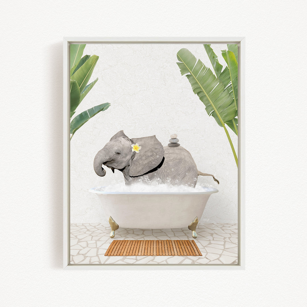 A gray elephant is sitting in a white bathtub filled with bubbles, surrounded by green leaves and a wooden mat on the floor.