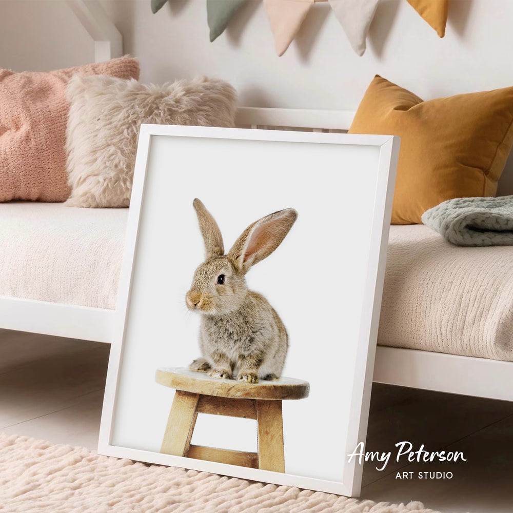 A framed image of a rabbit sitting on a wooden stool is displayed in a cozy living room setting.