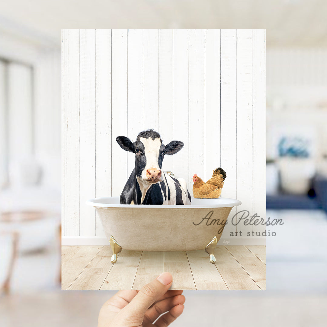 a hand holding up a photo of a cow in a bathtub