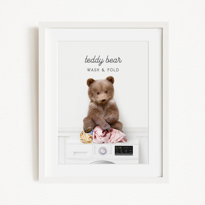 A teddy bear sitting on a washing machine, with the text "teddy bear" and "WASH & FOLD" written above it.