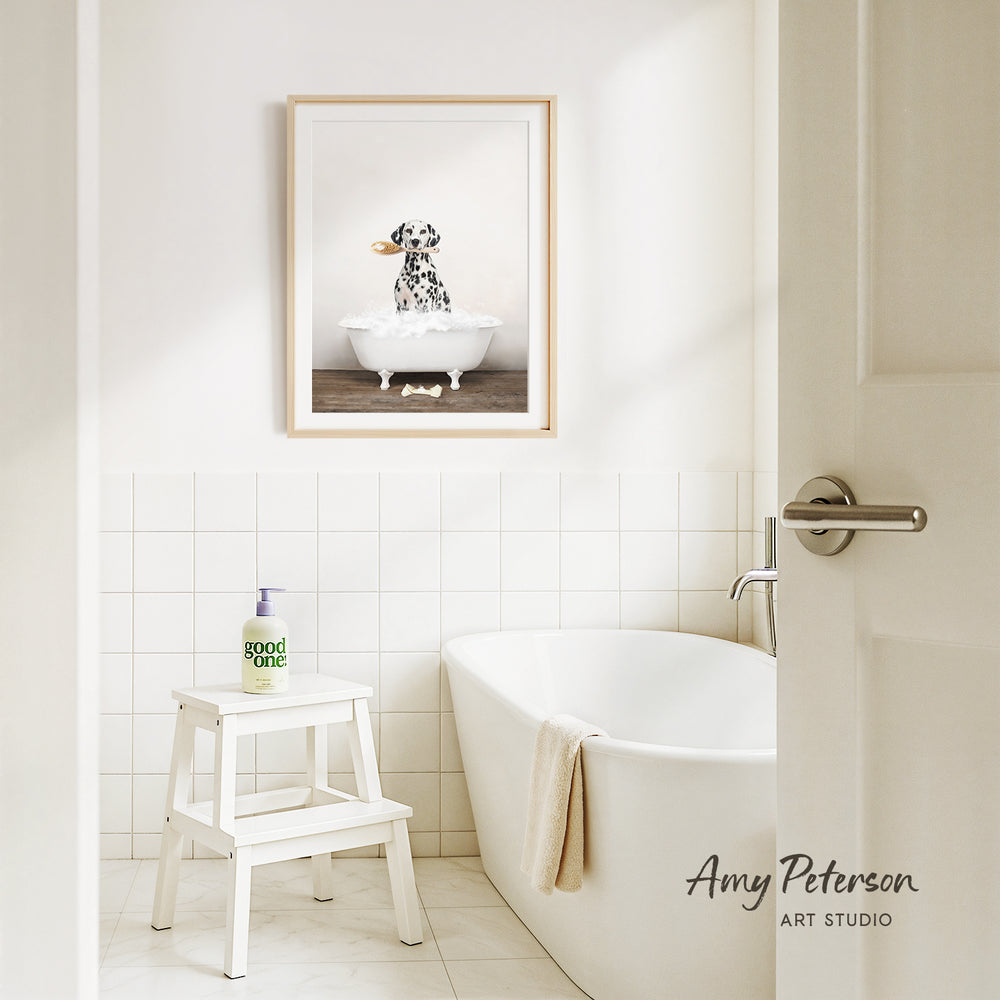 A framed image of a Dalmatian dog sitting in a bathtub is displayed on the wall above a white bathtub in a clean, minimalist bathroom.
