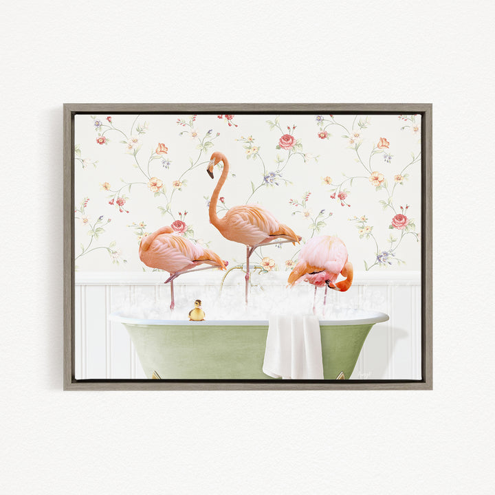 A framed image depicting three pink flamingos standing in a green bathtub, with a floral wallpaper in the background.