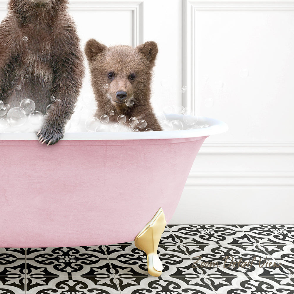 A baby bear sitting in a pink bathtub filled with bubbles, with a gold-colored bathtub leg visible.