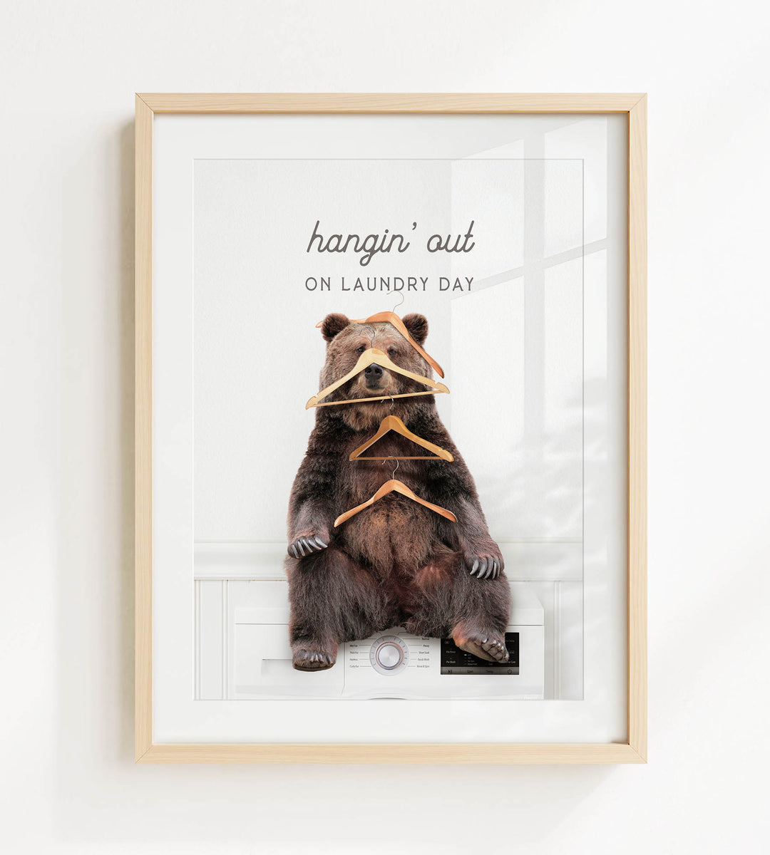 A framed image of a bear sitting on a washing machine, with a humorous caption that reads "hangin' out on laundry day".