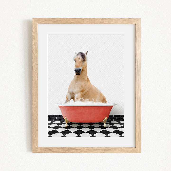 A light brown horse is sitting in a red bathtub filled with water, surrounded by a black and white checkered floor.