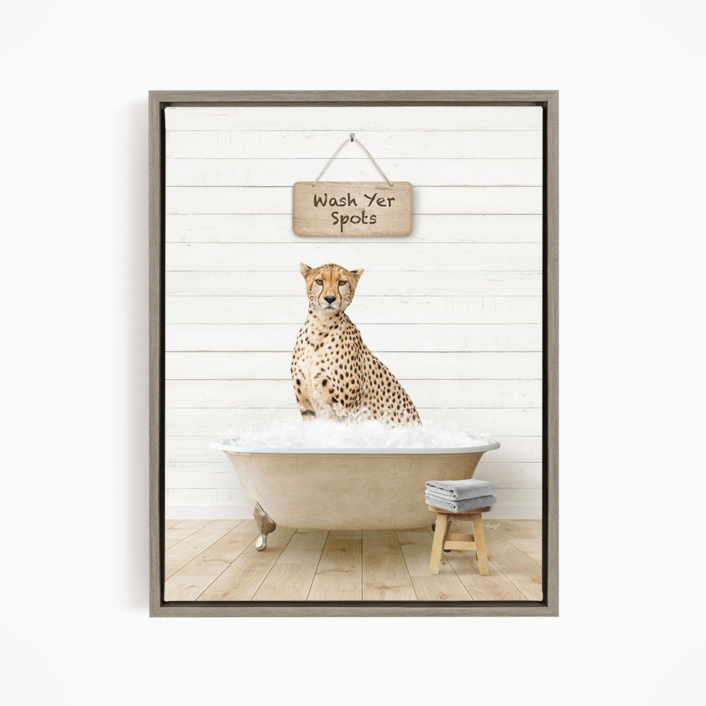 A cheetah sitting in a bathtub filled with water, with a wooden sign above that says "Wash Yer Spots".