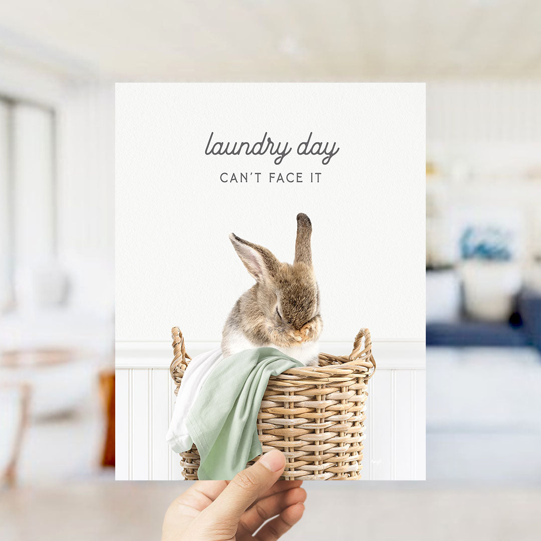 A hand holding a picture of a rabbit in a basket, with the text "laundry day can't face it" written above the image.