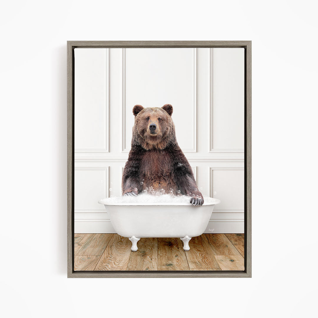 A brown bear sitting in a white bathtub, appearing to enjoy the bath.