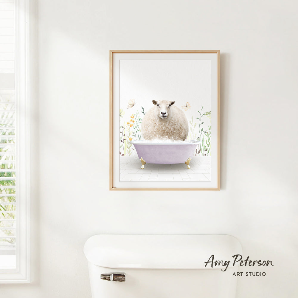 A framed print of a sheep sitting in a bathtub is hanging on a white wall.