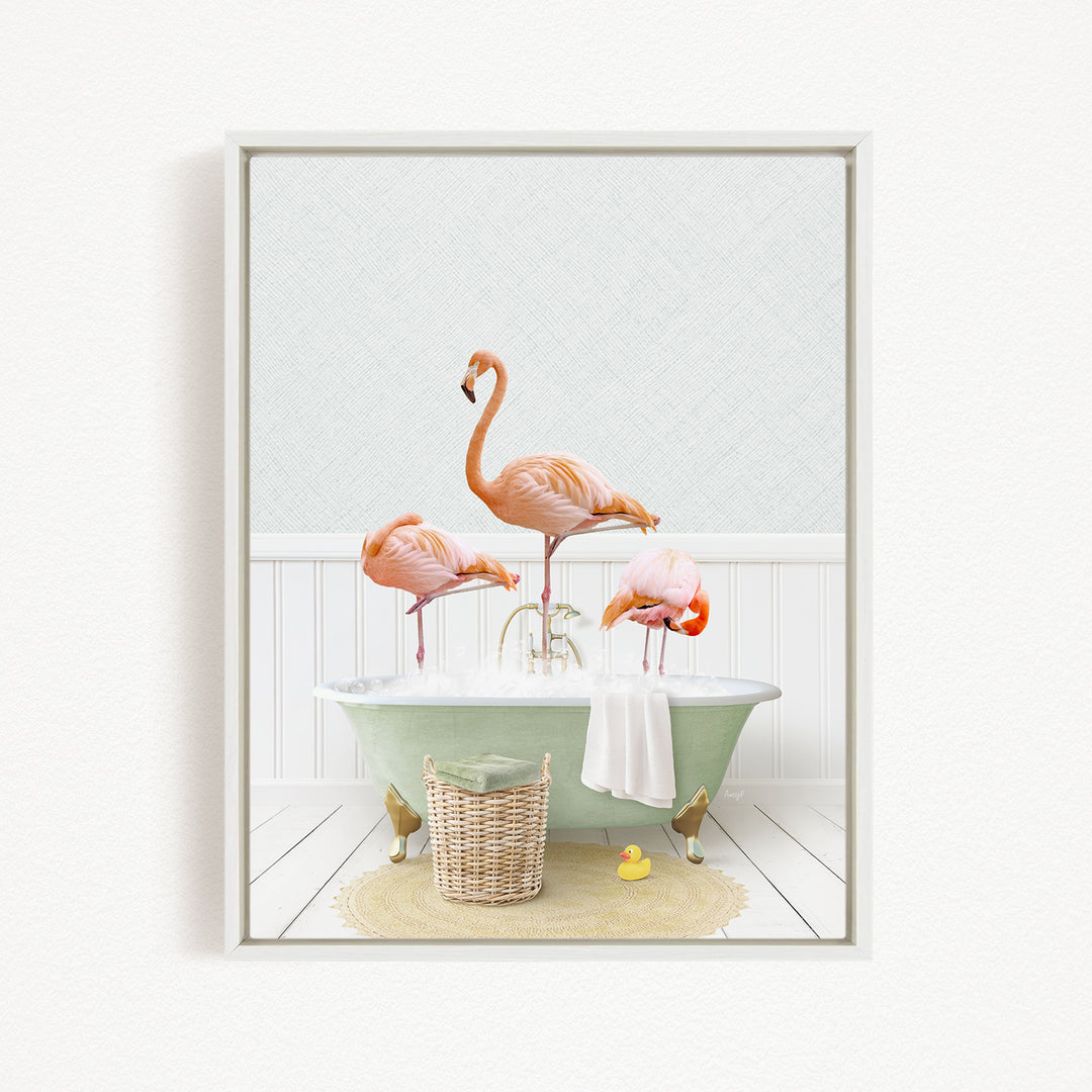 A framed image depicting three pink flamingos standing in a green bathtub filled with water, surrounded by a basket of bath toys and a yellow rubber duck.