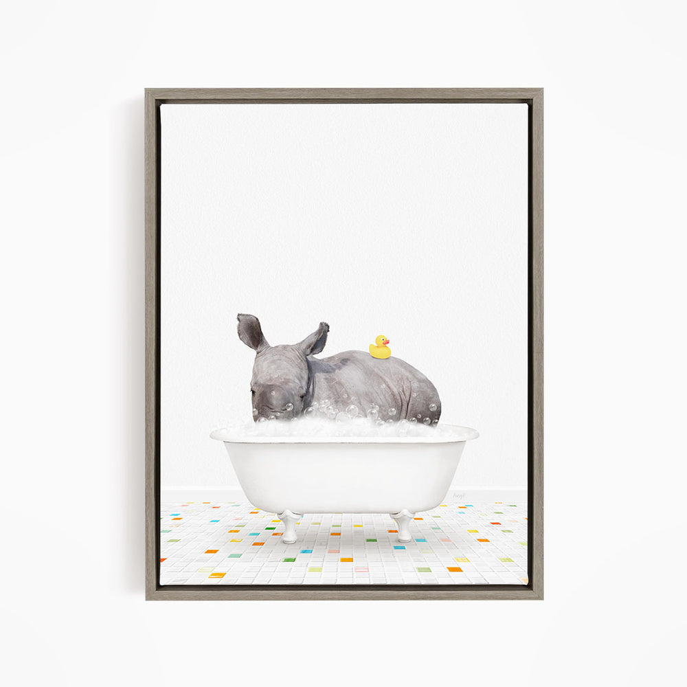 A rhinoceros is sitting in a white bathtub filled with water, with a yellow rubber duck floating on its back.