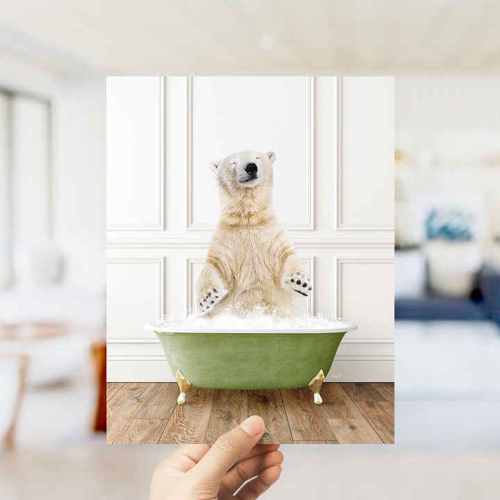 A polar bear sitting in a green bathtub filled with bubbles, with a person's hand holding the photo up to the camera.