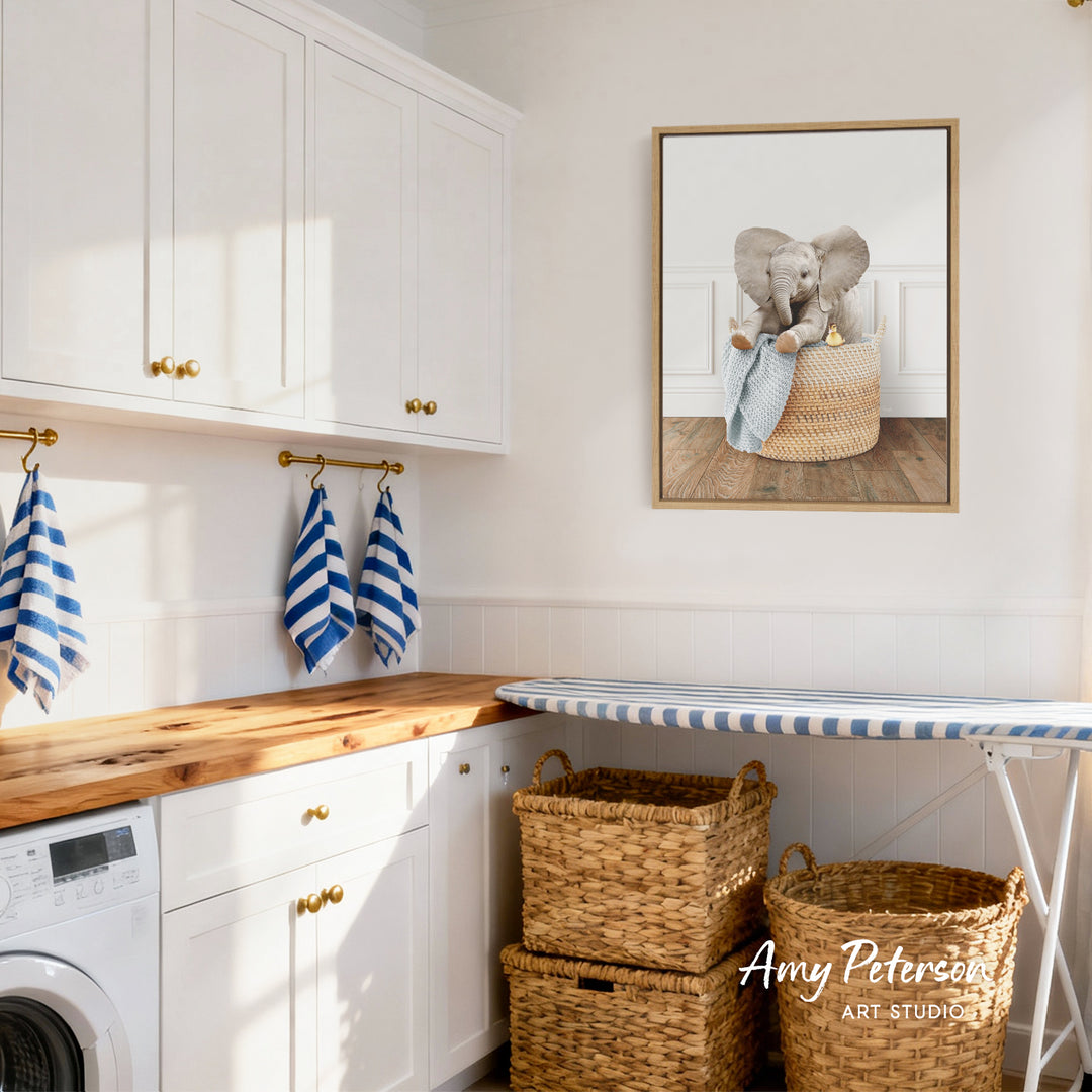 A cozy laundry room with white cabinets, a wooden countertop, and a framed image of an elephant sitting in a basket.