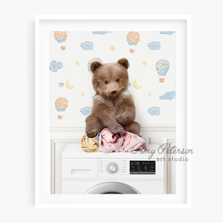 a teddy bear sitting on top of a washing machine