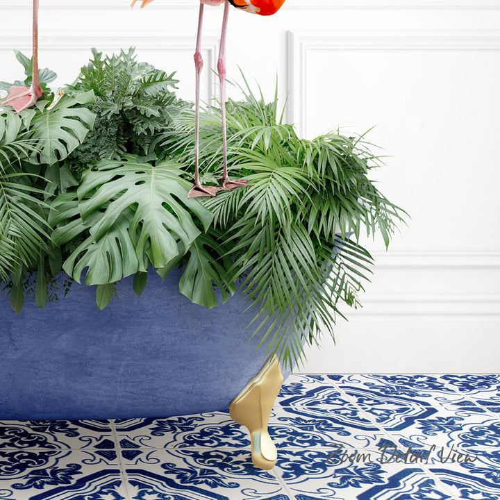 A large potted plant with lush green leaves and a pink flamingo perched on top, set against a white wall with a blue and white patterned tile floor.