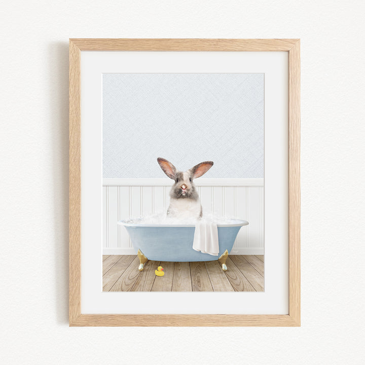 A rabbit sitting in a blue bathtub filled with bubbles, surrounded by yellow rubber duckies.