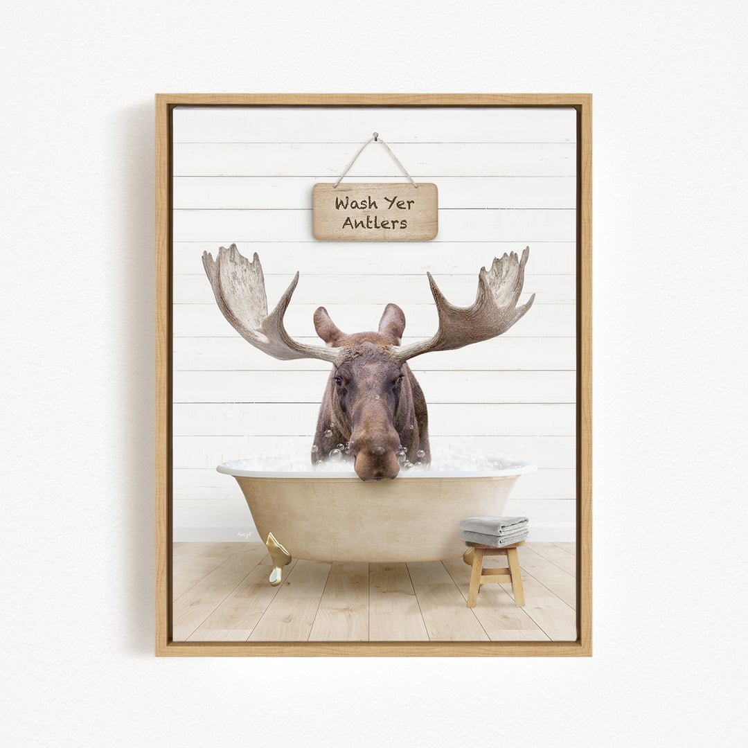 A moose is sitting in a bathtub filled with water, with a sign above it that says "Wash Yer Antlers".