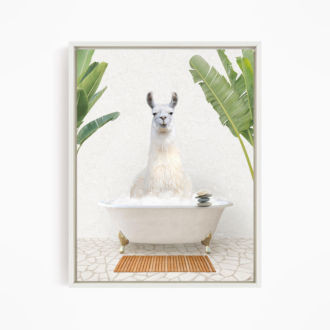 A white llama sitting in a white bathtub filled with bubbles, surrounded by green leaves and a wooden mat on the floor.