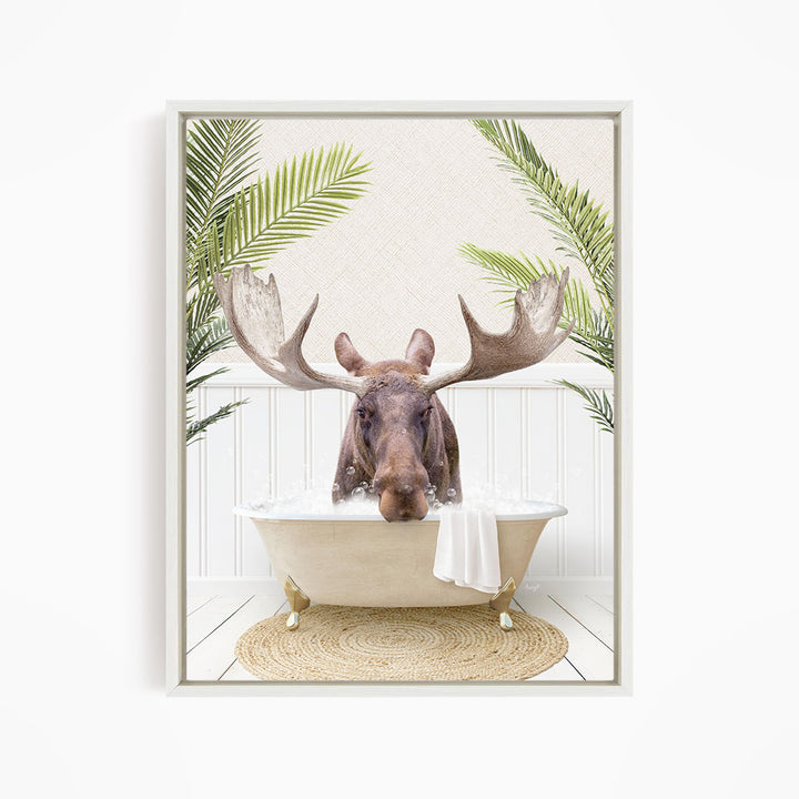 A moose with large antlers is sitting in a bathtub filled with water, surrounded by palm leaves and a woven rug.