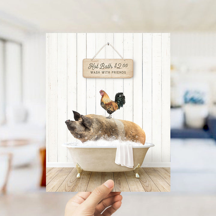 A hand holding a framed image of a pig sitting in a bathtub, with a rooster perched on its back, and a sign above the bathtub that reads "Hot Bath $2.00 WASH WITH FRIENDS".
