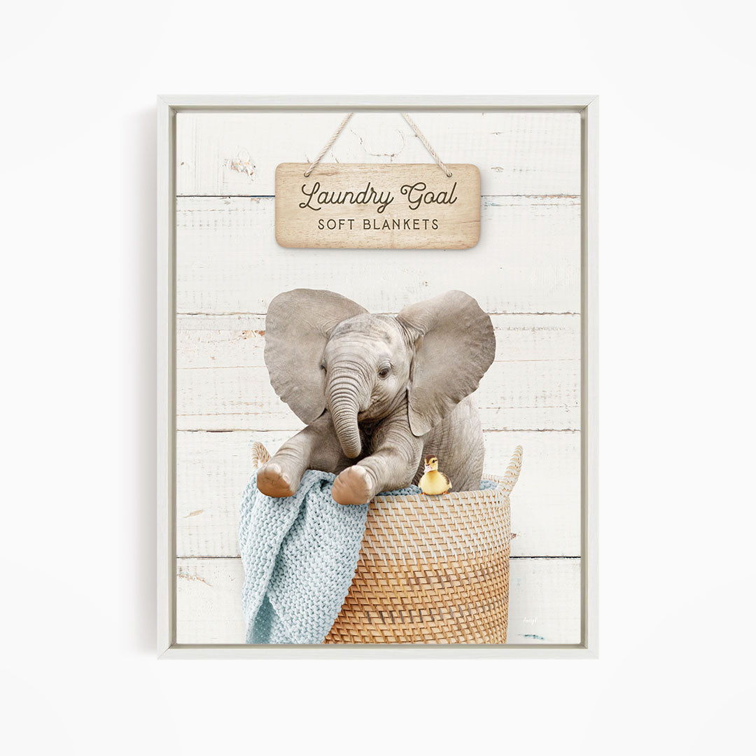 A gray elephant sitting in a woven basket, with a sign above it that says "Laundry Goal Soft Blankets".