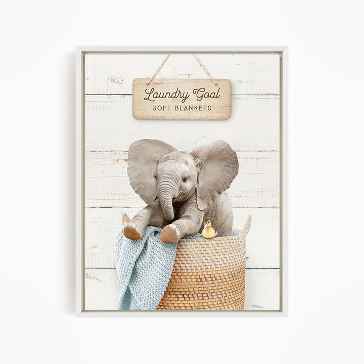 A gray elephant sitting in a woven basket, with a sign above it that says "Laundry Goal Soft Blankets".